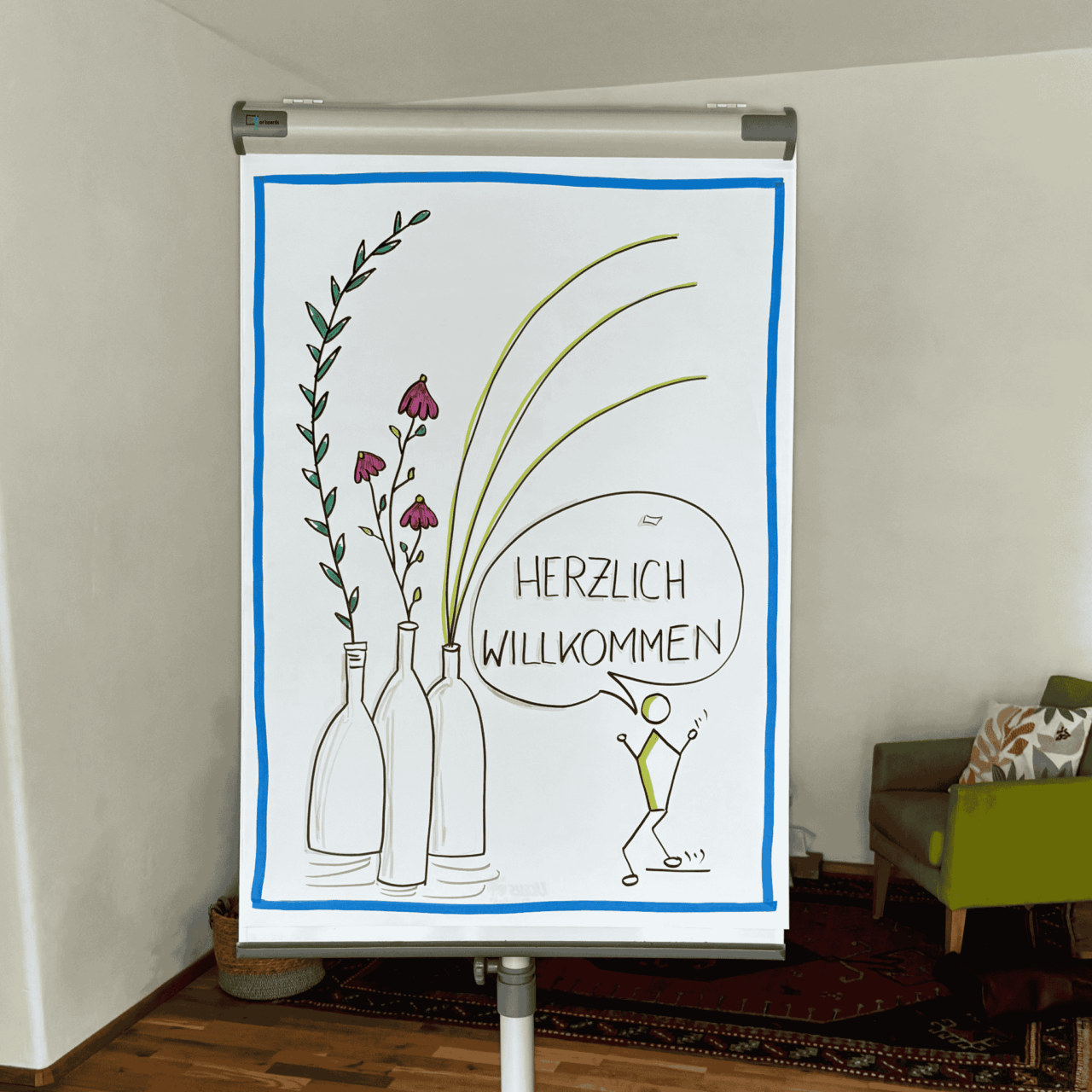 Angela Peichl | Flupchart steht im Raum. Es sind Blumen zu sehen und Herzlich Willkommen steht geschrieben